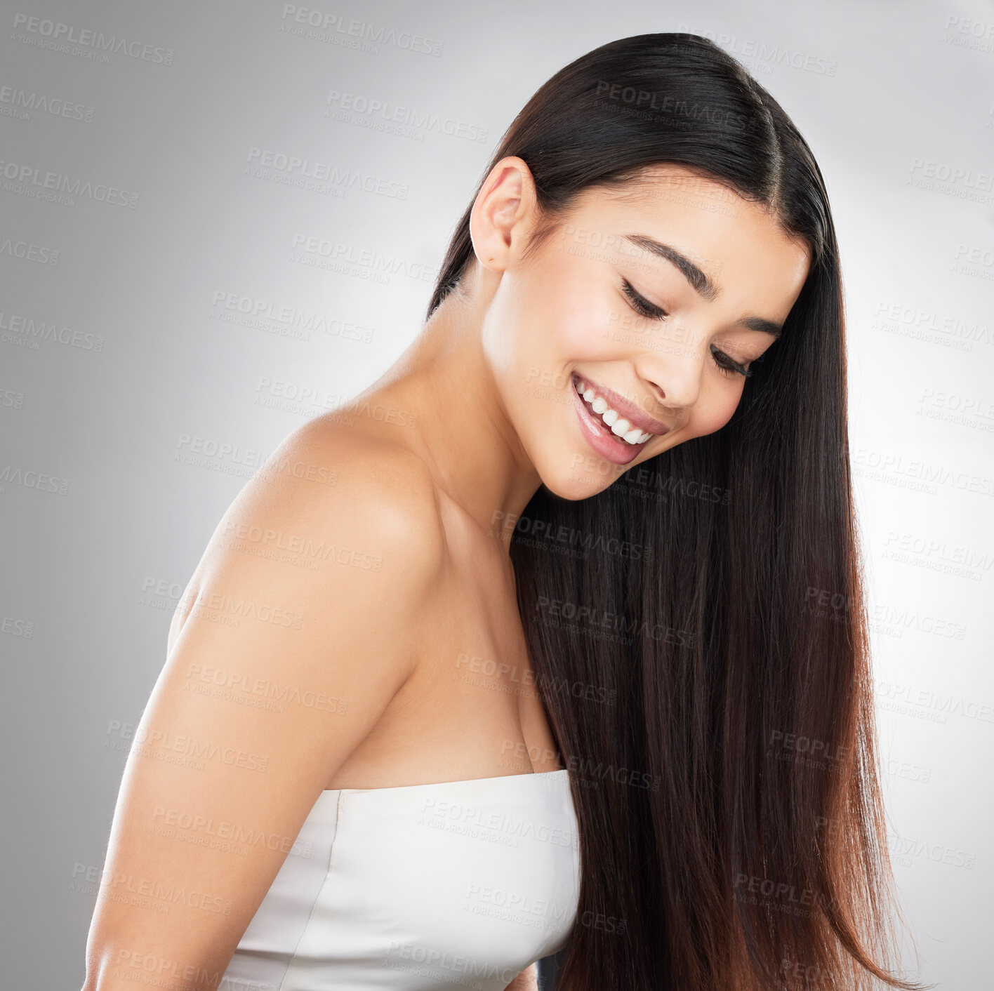 Buy stock photo Studio shot of a beautiful young woman showing off her long silky hair against a grey background