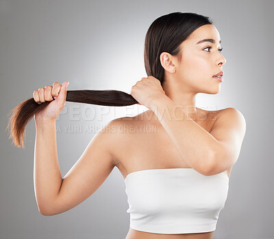 Buy stock photo Studio shot of a beautiful young woman showing off her long silky hair against a grey background