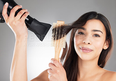 Buy stock photo Studio portrait of a beautiful young woman styling her hair against a grey background