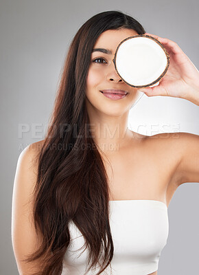 Buy stock photo Woman, haircare and coconut in studio, happy or smile for self care, nutrition or cosmetic health. Model, hair treatment or fruit for oil, moisturizer or aesthetic for natural glow on gray background