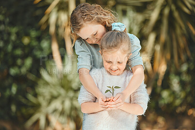 Buy stock photo Shot of sisters holding a plant outside