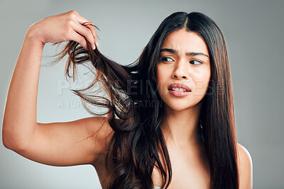 Buy stock photo Studio shot of a young woman looking unhappy with her hair