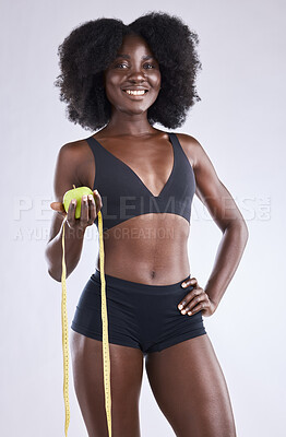 Buy stock photo Studio shot of a woman holding an apple and a measuring tape