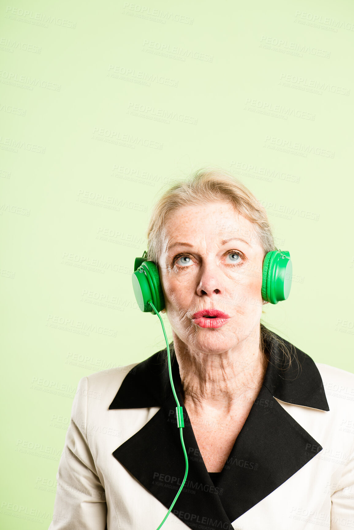 Buy stock photo Shot of a senior woman sitting alone in the studio and listening to music through headphones
