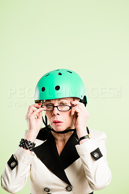 Buy stock photo Shot of a senior woman sitting alone in the studio and posing while wearing a helmet and glasses