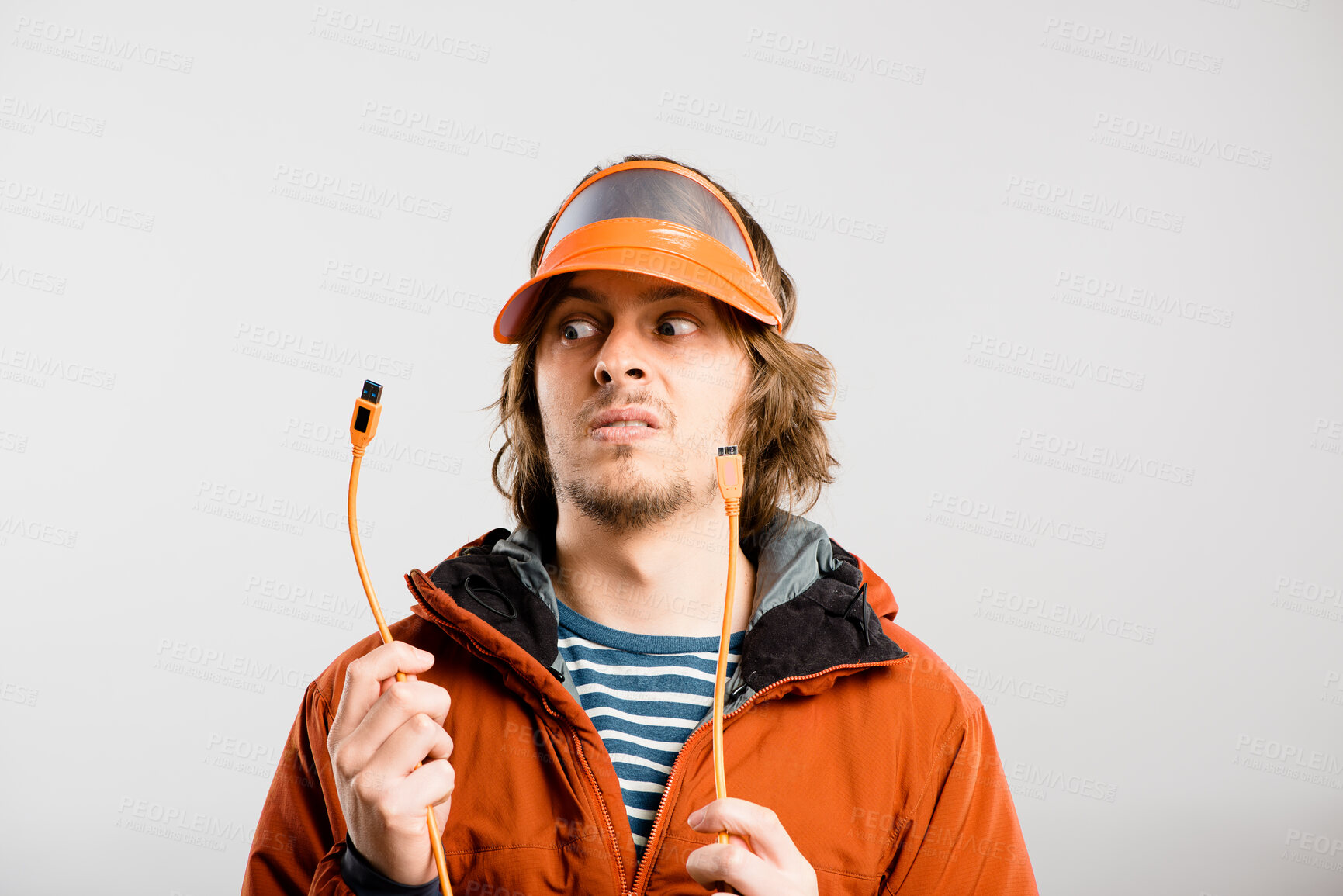 Buy stock photo Cable, confused and man in studio upset with faulty wire for bad power supply connection. Annoyed, mockup space and male electrician with charger for fixing with tech career by white background.