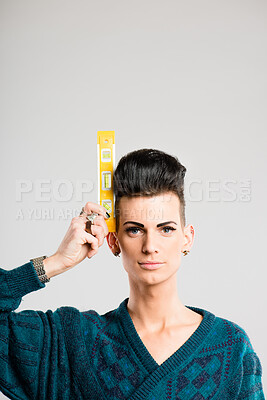 Buy stock photo Shot of a handsome young man standing alone in the studio and holding a water spirit level tool