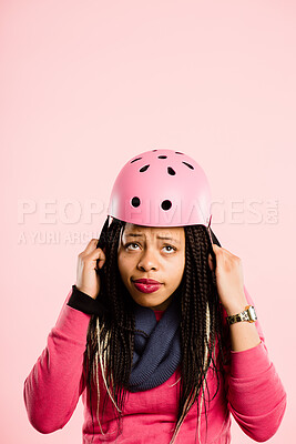 Buy stock photo Shot of an attractive young woman sitting alone in the studio and putting a helmet on