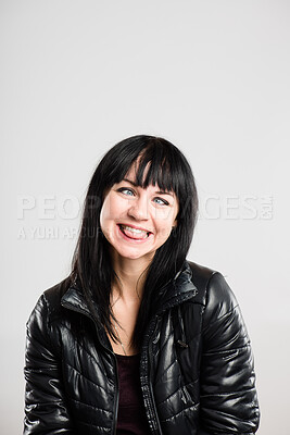 Buy stock photo Shot of an attractive young woman sitting alone in the studio and pulling funny faces