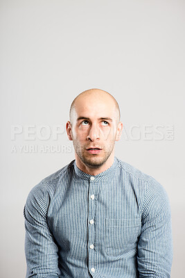 Buy stock photo Shot of a handsome young man sitting alone in studio and looking bored