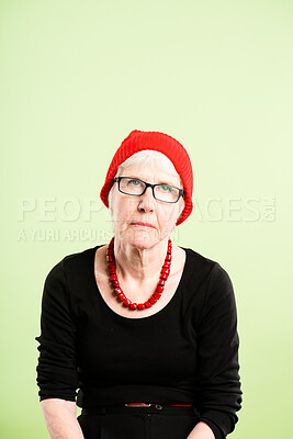 Buy stock photo Shot of a senior woman sitting alone in the studio and looking bored while wearing a beanie