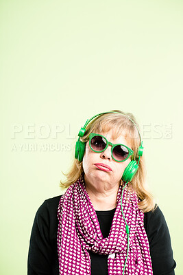 Buy stock photo Shot of a mature woman standing alone in the studio and listening to music through headphones