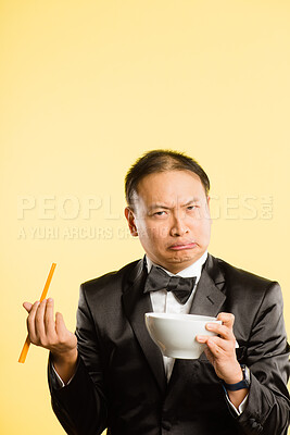 Buy stock photo Man, chopsticks and portrait in studio with funny face, tuxedo and confused with bowl by background. Chinese person, container and comic for nutrition, eating and choice for diet with suit in China