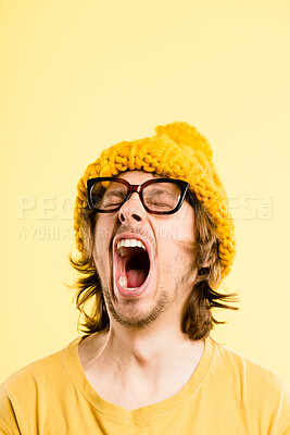 Buy stock photo Shot of a handsome young man standing alone in the studio and yawning