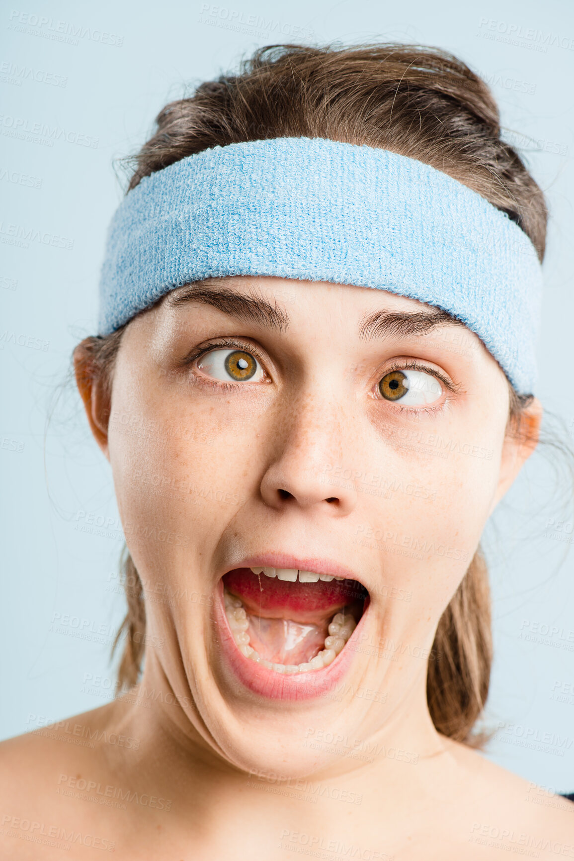 Buy stock photo Shot of an attractive young woman standing alone in the studio and pulling funny faces while wearing a headband