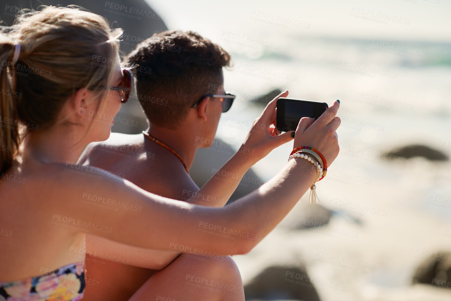 Buy stock photo Shot of a couple taking selfies while relaxing at the beach