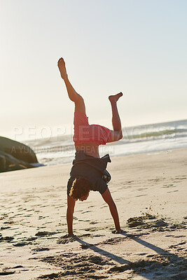 Buy stock photo Shot of a man performing a headstand at the beach