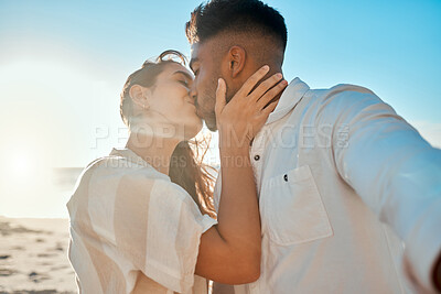 Buy stock photo Shot of a young couple kissing while spending a day at the beach