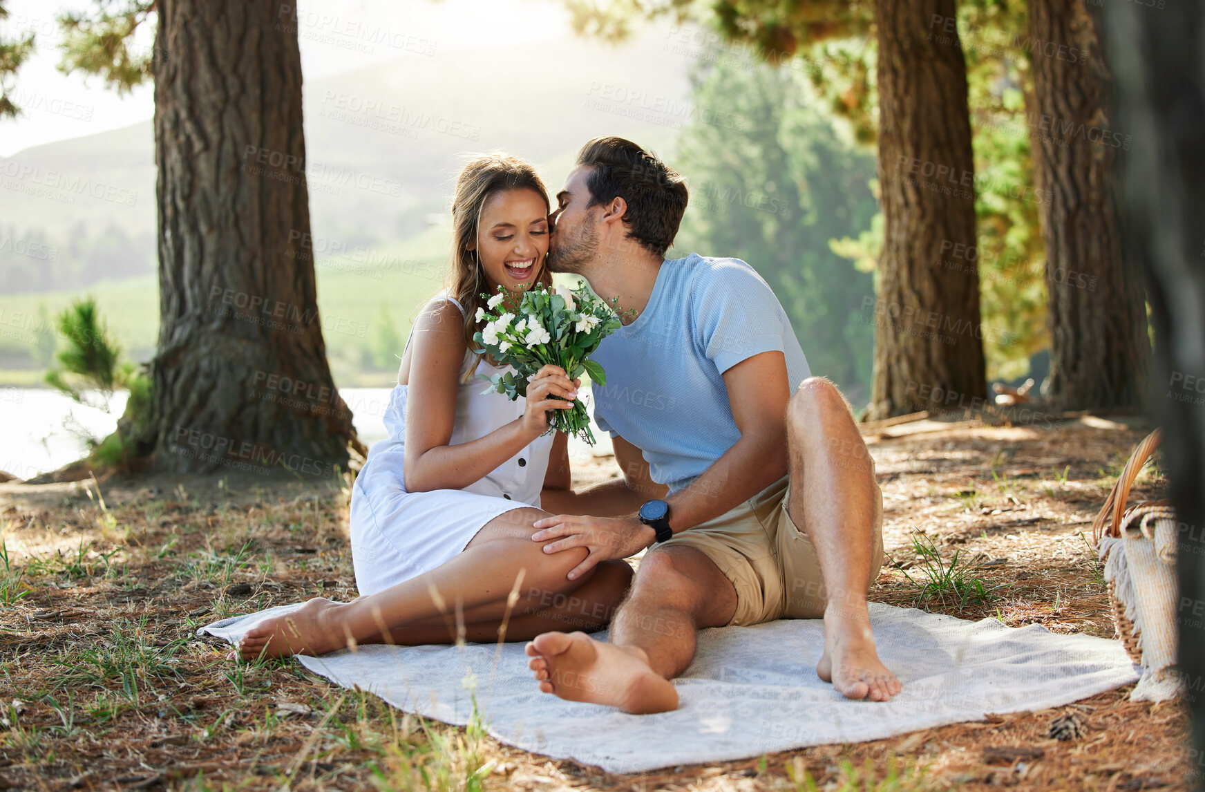 Buy stock photo Couple kiss, love and flowers on picnic, summer with freedom and adventure, affection in relationship and care outdoor. Happy people together in nature, commitment and trust with romance in forest