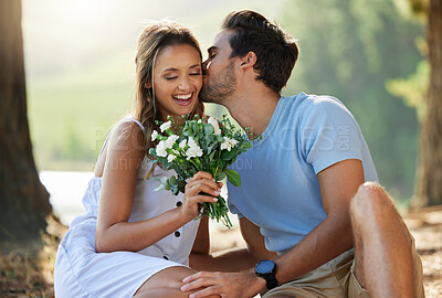 Buy stock photo Man kiss woman, picnic with flowers in park with happy couple in nature, love with bonding and relax outdoor. Commitment, trust and relationship, people smile with summer and holiday with travel