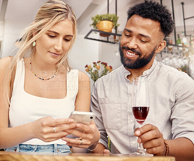 Buy stock photo Shot of a young couple using a smartphone together at a restaurant