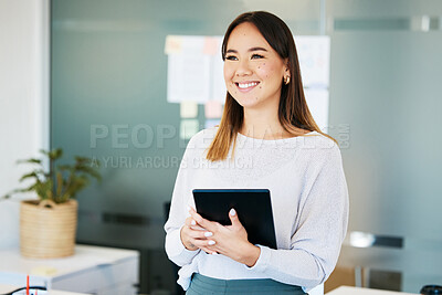 Buy stock photo Shot of an attractive young businesswoman standing alone in the office and holding a digital tablet