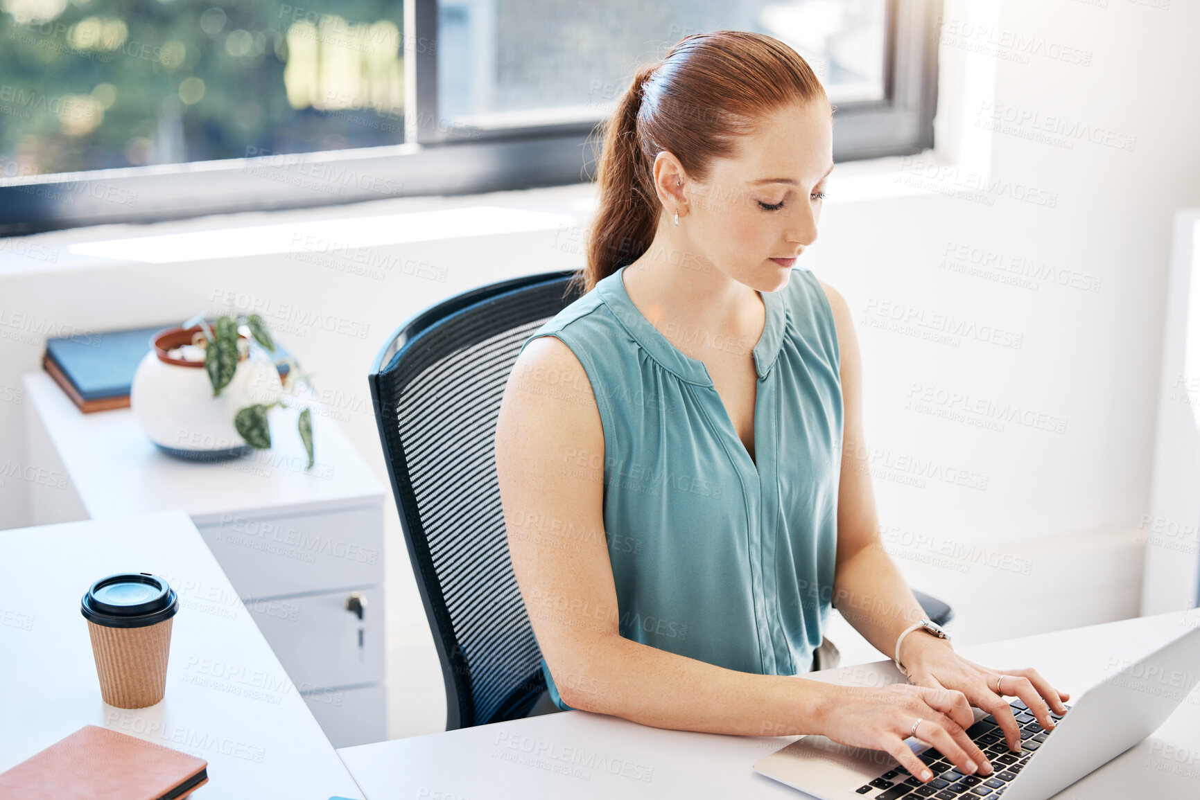 Buy stock photo Shot of an attractive young businesswoman sitting alone in the office and using her laptop