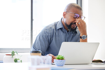 Buy stock photo Shot of a handsome mature businessman sitting alone in the office and feeling stressed while using his laptop