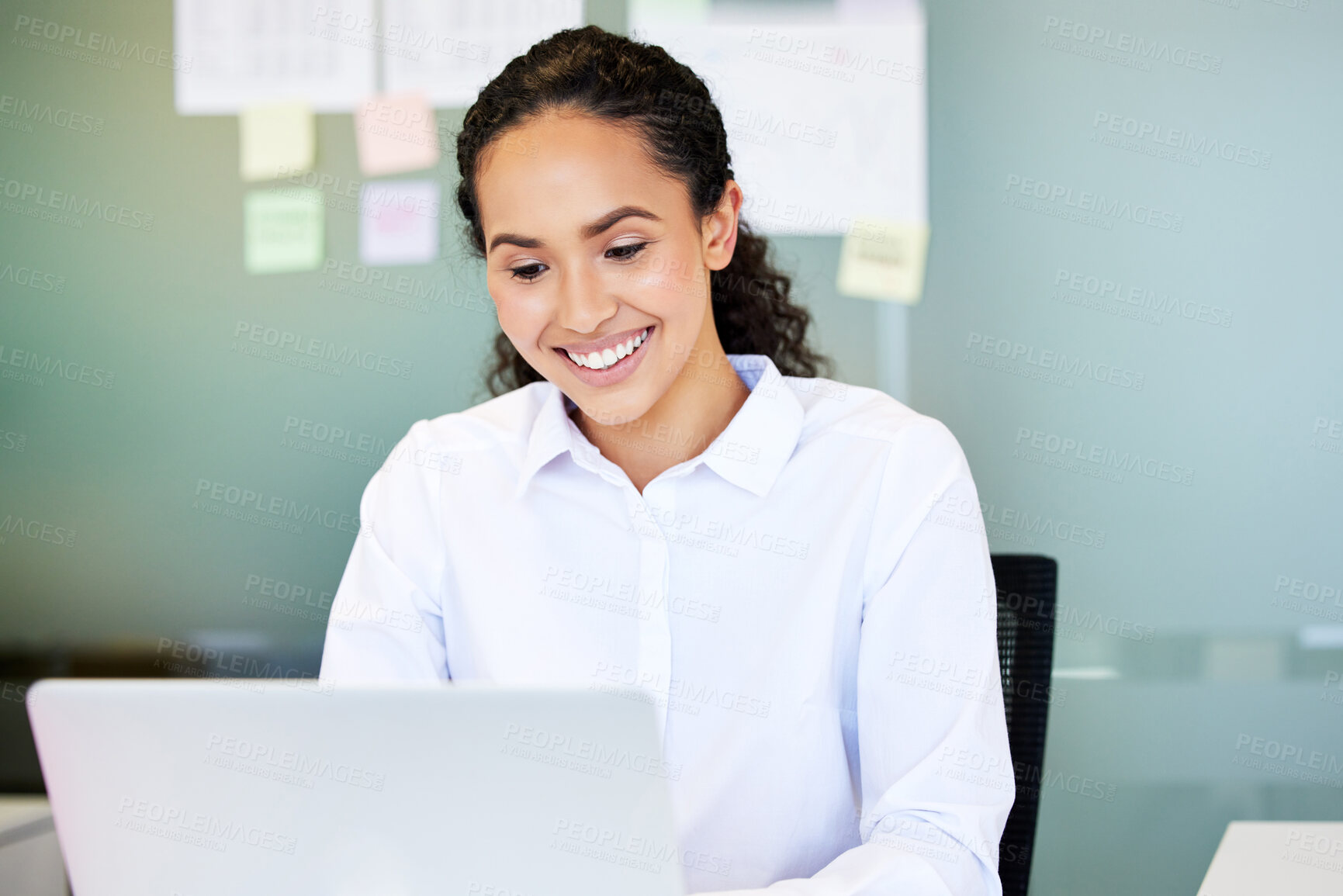 Buy stock photo Shot of an attractive young businesswoman sitting alone in the office and using her laptop