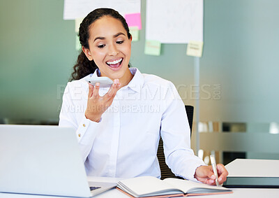 Buy stock photo Shot of an attractive young businesswoman sitting alone in the office and using her cellphone while writing notes
