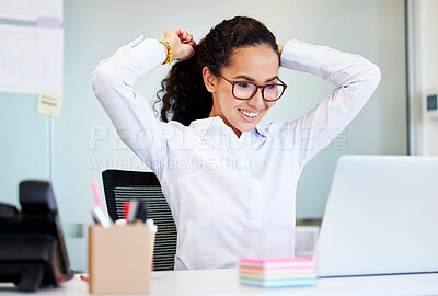 Buy stock photo Shot of an attractive young businesswoman sitting alone in the office and tying her hair before using her laptop
