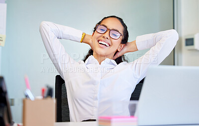 Buy stock photo Shot of an attractive young businesswoman sitting alone in the office and feeling successful with her hands behind her head