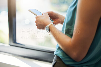 Buy stock photo Cropped shot of an unrecognisable businesswoman standing alone in the office and using her cellphone