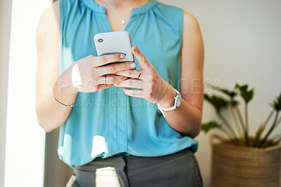 Buy stock photo Cropped shot of an unrecognisable businesswoman standing alone in the office and using her cellphone