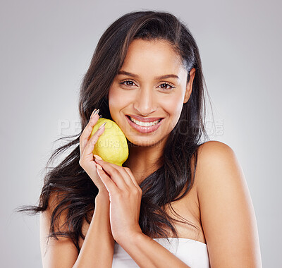 Buy stock photo Cropped portrait of an attractive young woman posing with a lemon against a grey background