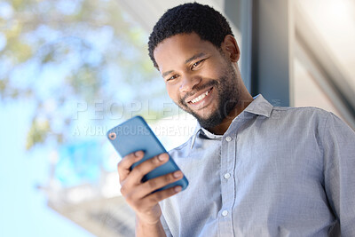 Buy stock photo Black man, typing and reading with phone by window for communication, social media or news at office. Happy businessman, employee or smile on mobile smartphone for online chat or texting at workplace