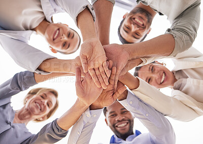 Buy stock photo Low angle shot of a group of businesspeople joining their hands together in a huddle in an office