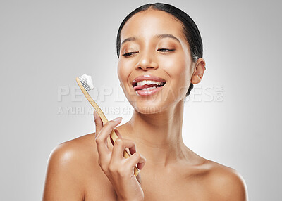 Buy stock photo Studio shot of an attractive young woman sticking out her tongue while brushing her teeth against a grey background