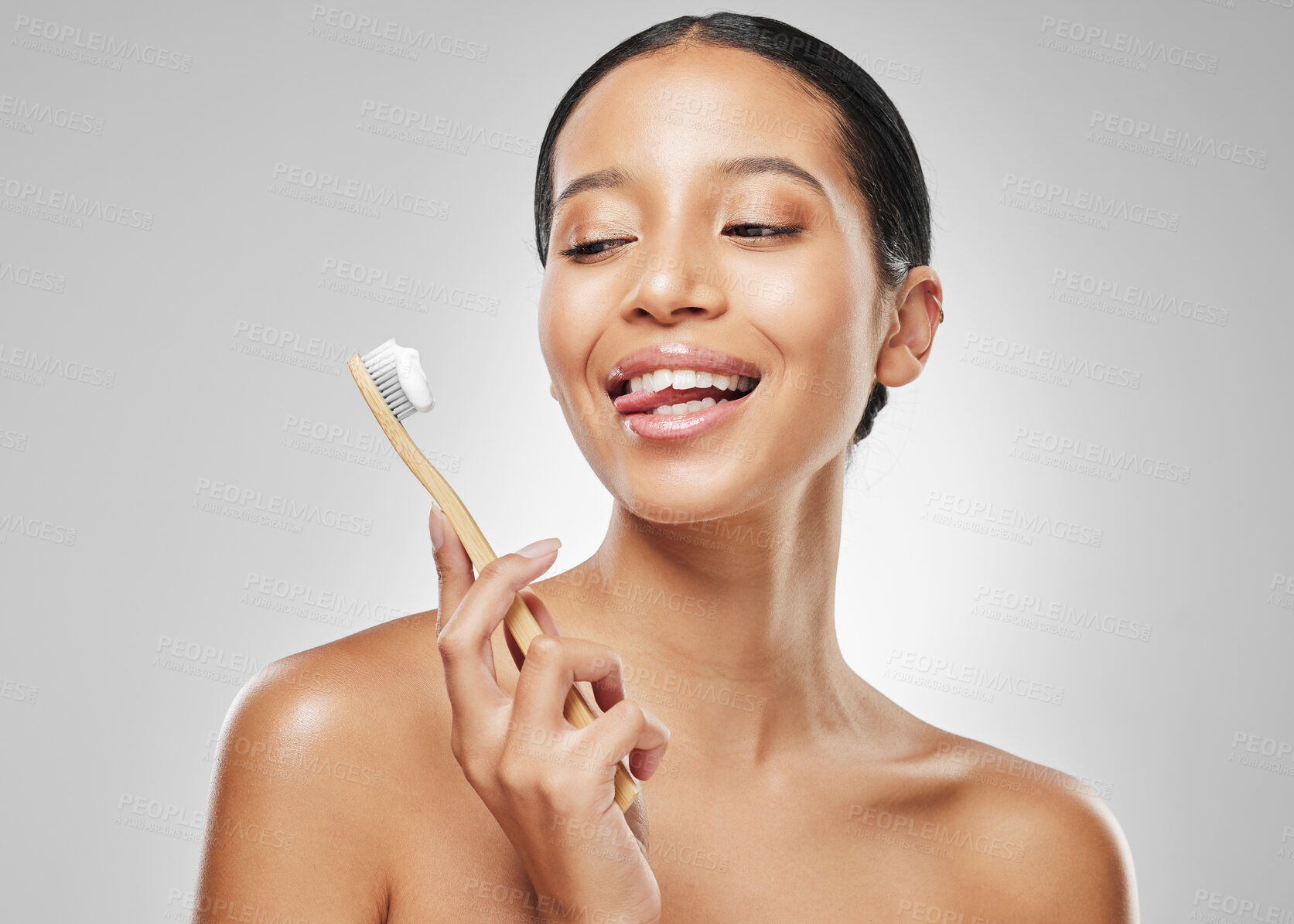 Buy stock photo Studio shot of an attractive young woman sticking out her tongue while brushing her teeth against a grey background