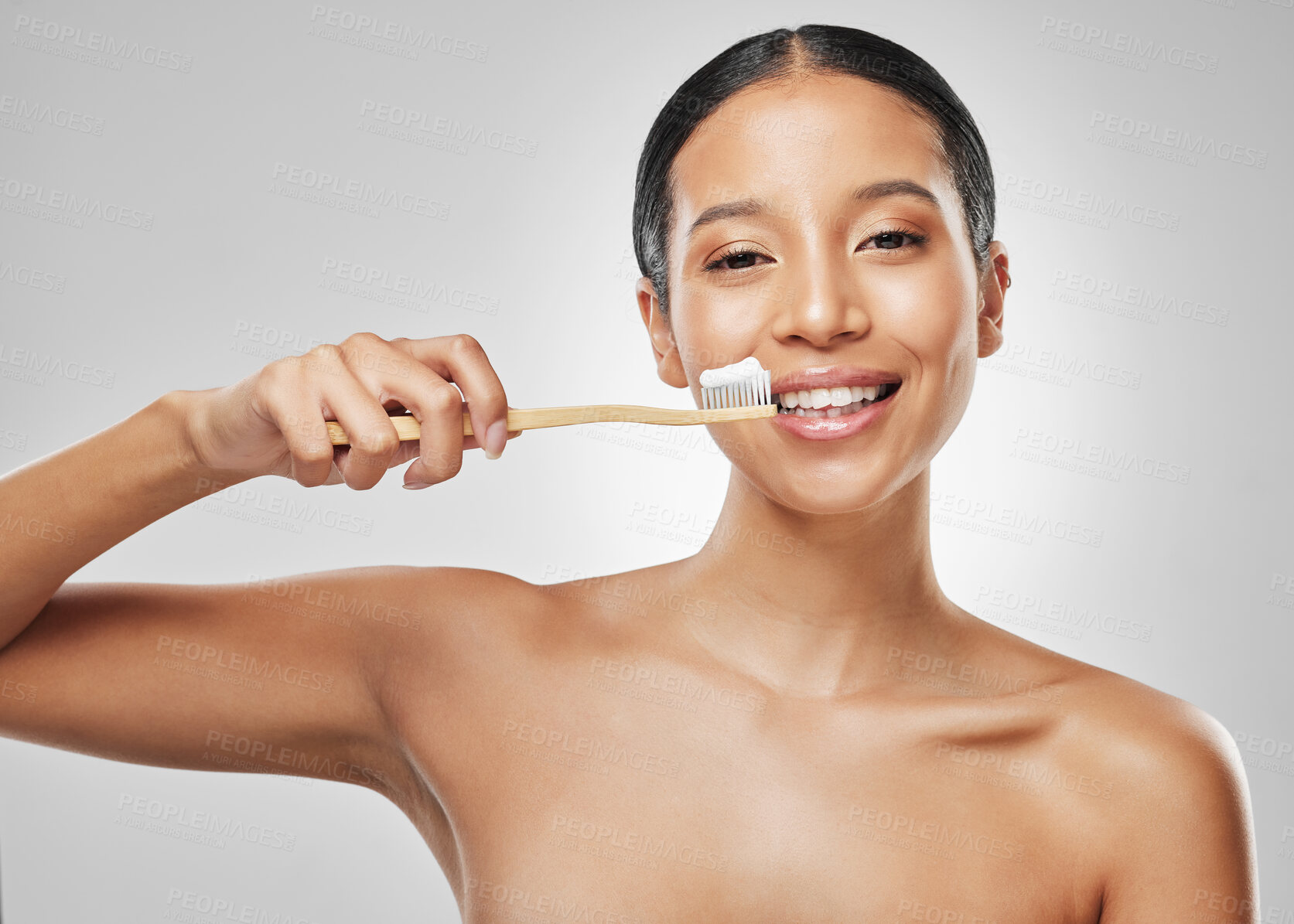 Buy stock photo Studio portrait of an attractive young woman brushing her teeth against a grey background