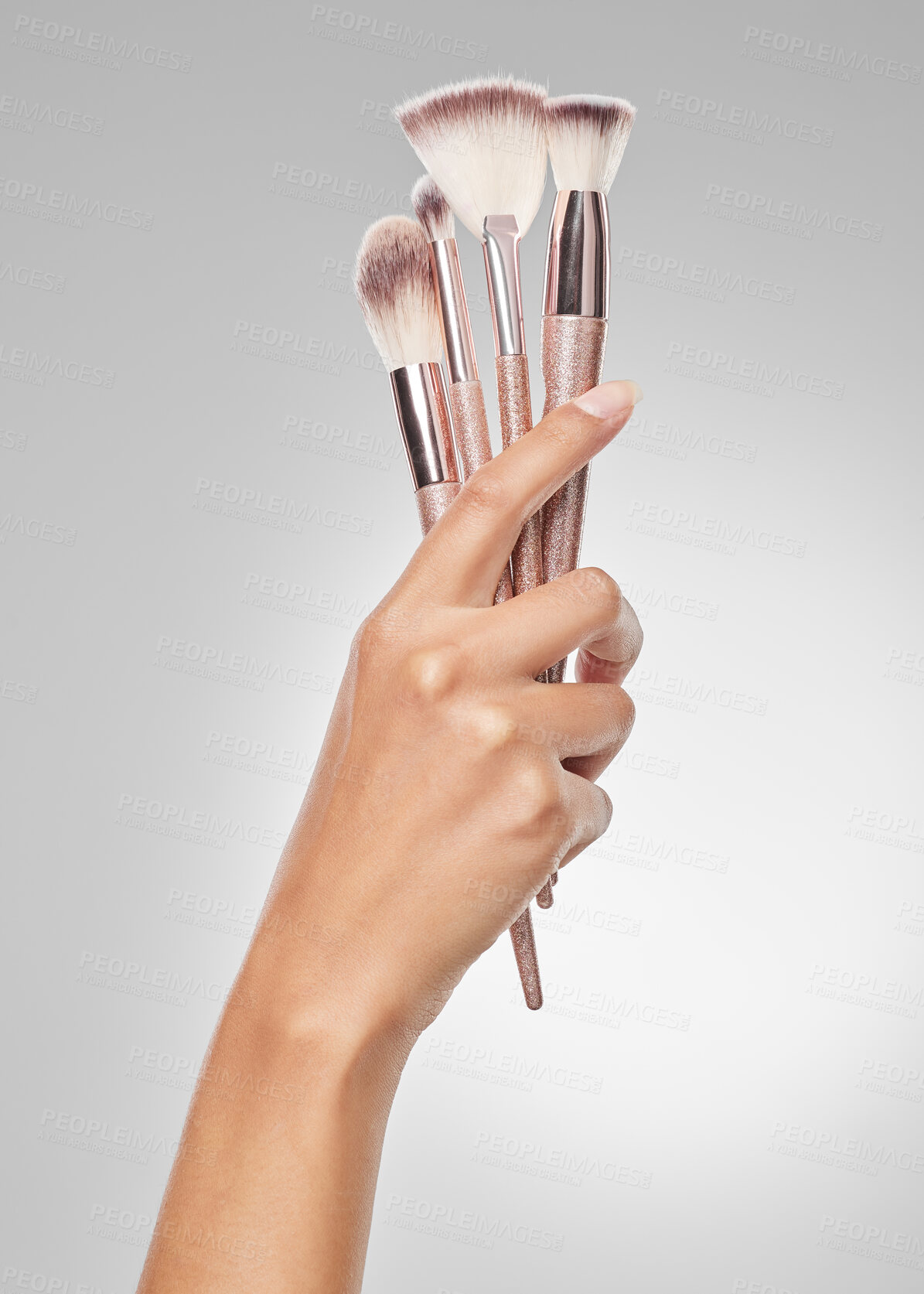 Buy stock photo Studio shot of a unrecognisable woman holding a collection of makeup brushes against a grey background