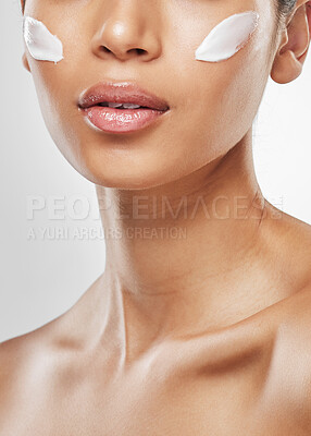 Buy stock photo Studio shot of an unrecognisable woman posing with moisturiser on her face against a grey background