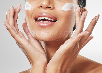 Buy stock photo Studio shot of an unrecognisable woman applying moisturiser on her face against a grey background