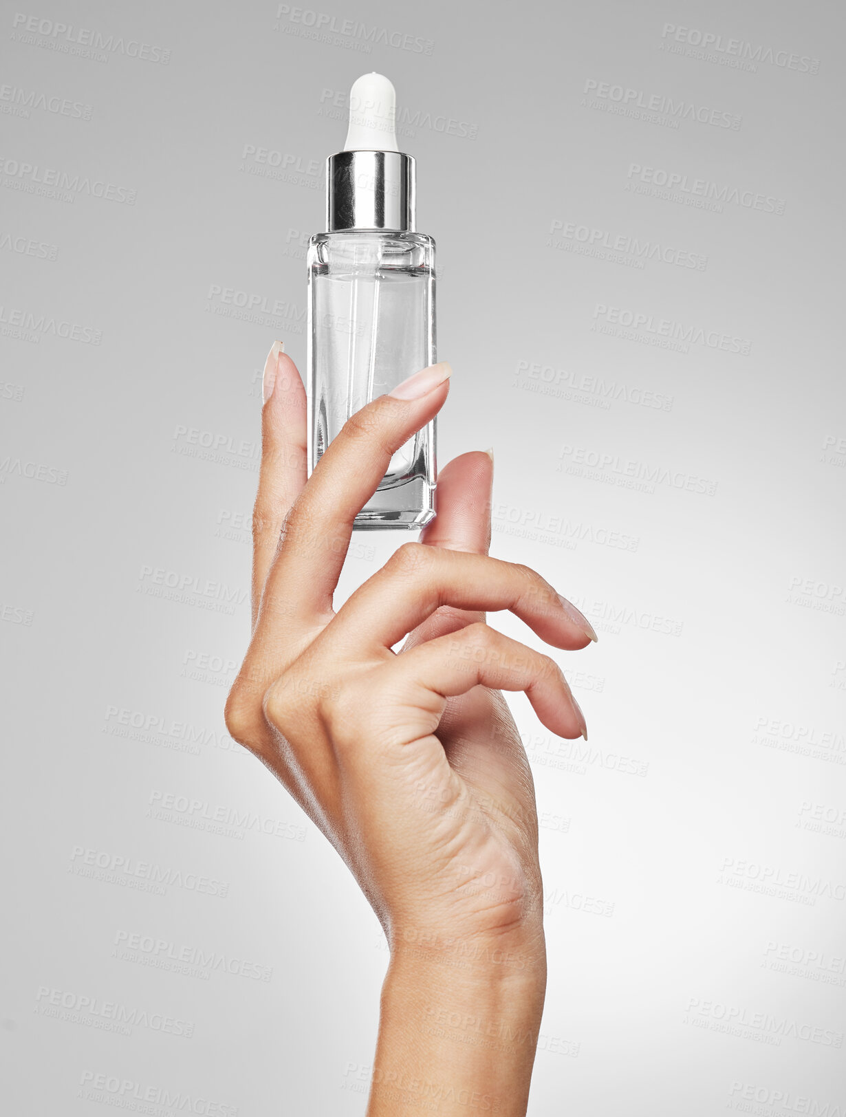 Buy stock photo Studio shot of an unrecognisable woman holding a bottle of serum against a grey background