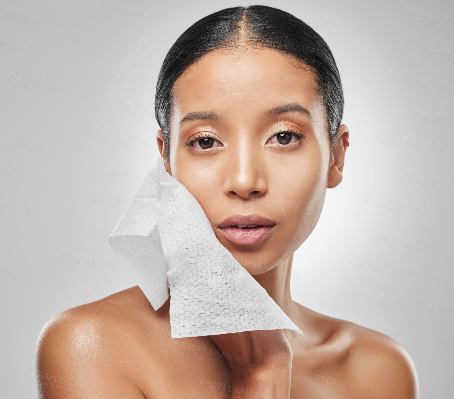 Buy stock photo Studio portrait of an attractive young woman using a facial wipe against a grey background