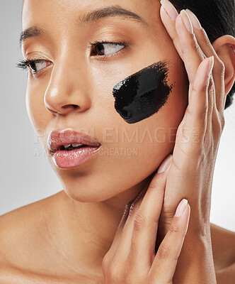 Buy stock photo Studio shot of an attractive young woman wearing some charcoal face mask against a grey background
