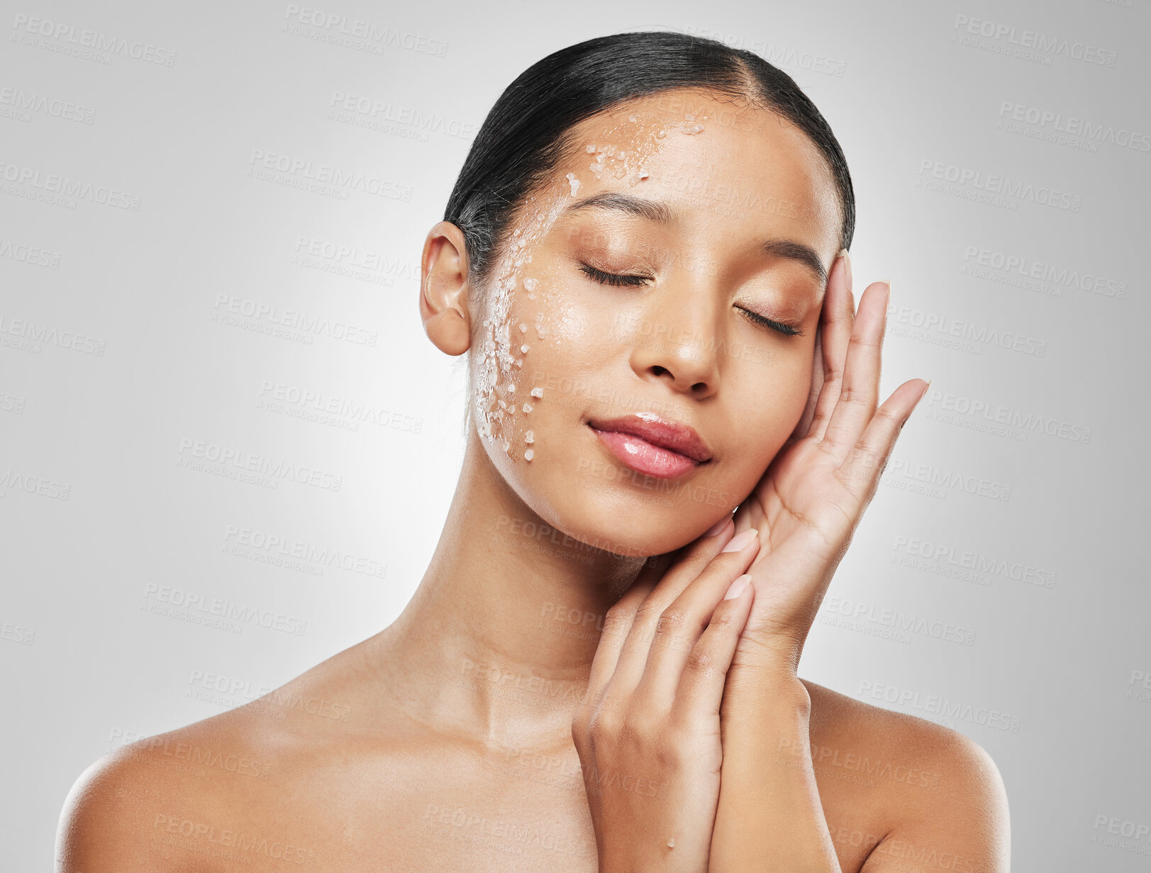 Buy stock photo Studio shot of an attractive young woman posing with sea salt scrub on her face against a grey background