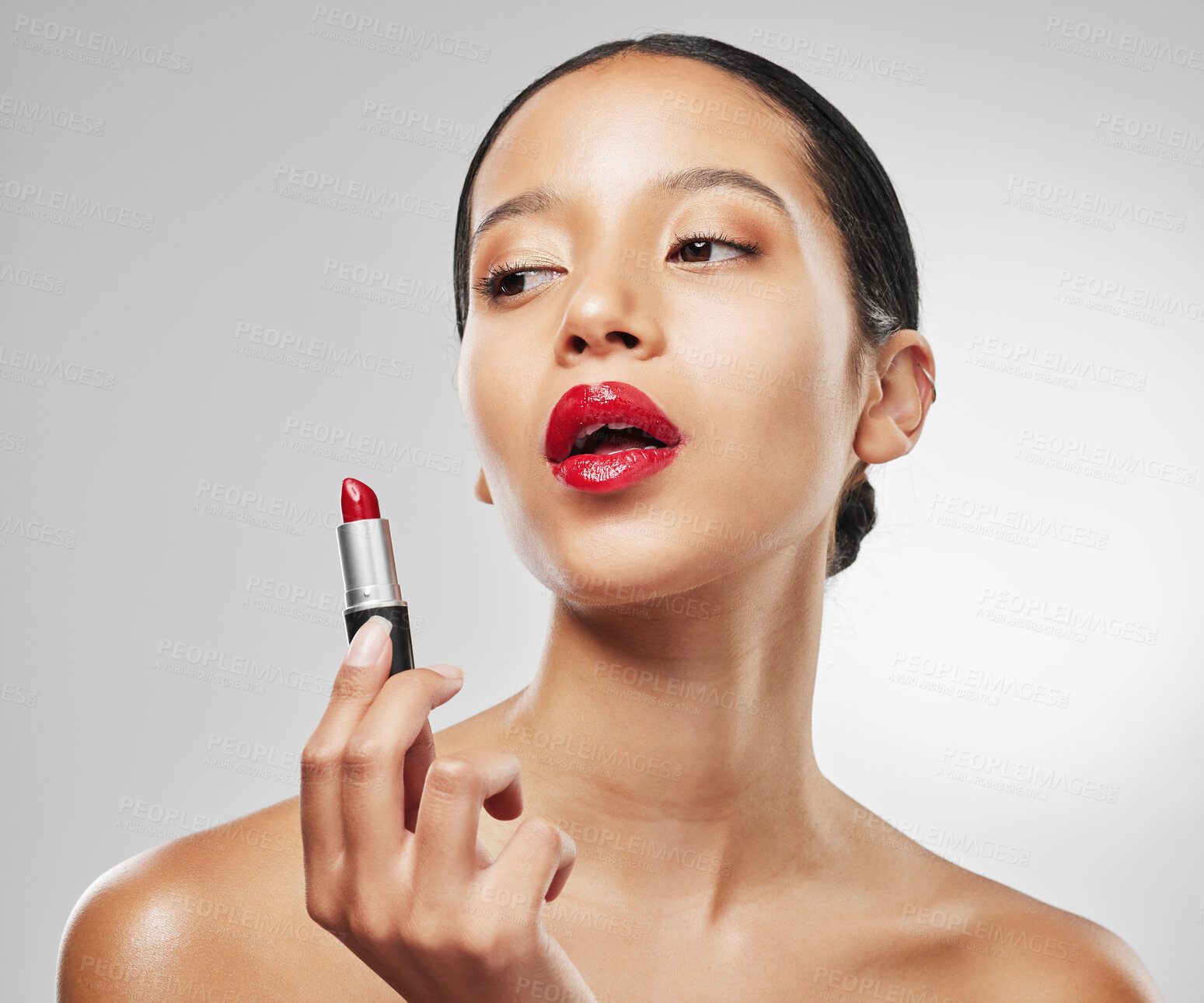 Buy stock photo Studio shot of a young woman applying red lipstick against a grey background