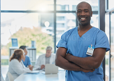 Buy stock photo Cropped portrait of a handsome young male nurse standing in the hospital boardroom while his colleagues meet in the background