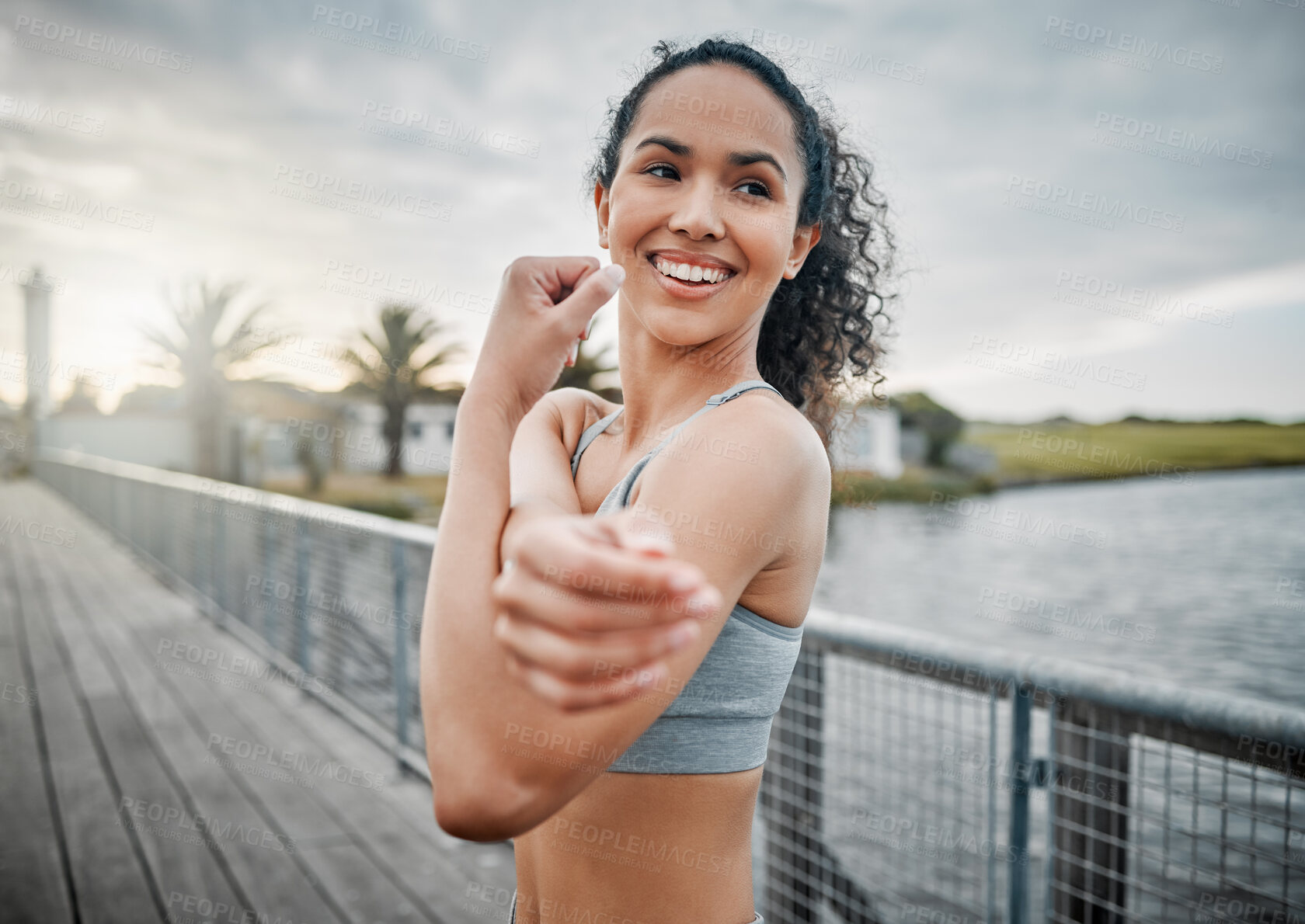 Buy stock photo Woman, smile and stretching arms for fitness, running and cardio exercise in morning with lake outdoor. Female person, muscle and warm up on bridge for health, training and workout with happiness